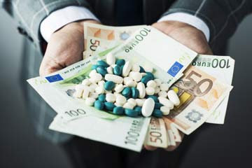 Geschäftsmann mit Pillen und Euroscheinen